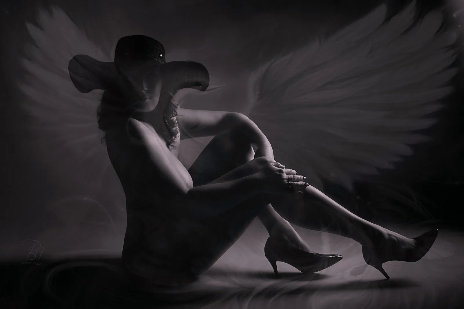 Angel on the ground — Photo: Norbert Banhalmi A winged figure sits on the ground in high heels, wings spread behind her.