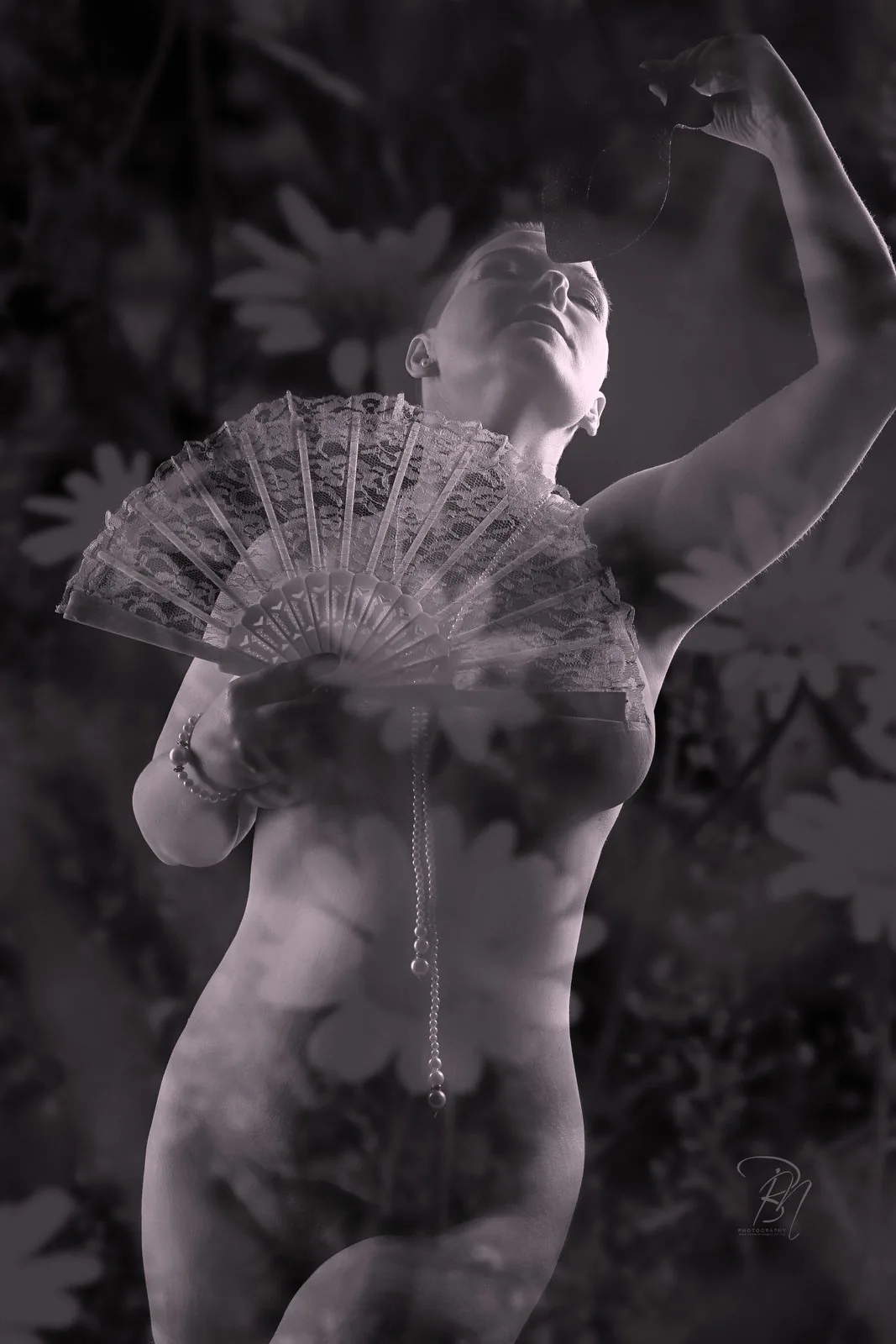 Fan and flowers — Photo: Norbert Banhalmi A woman raises a lace fan, flowers filling the frame around her.