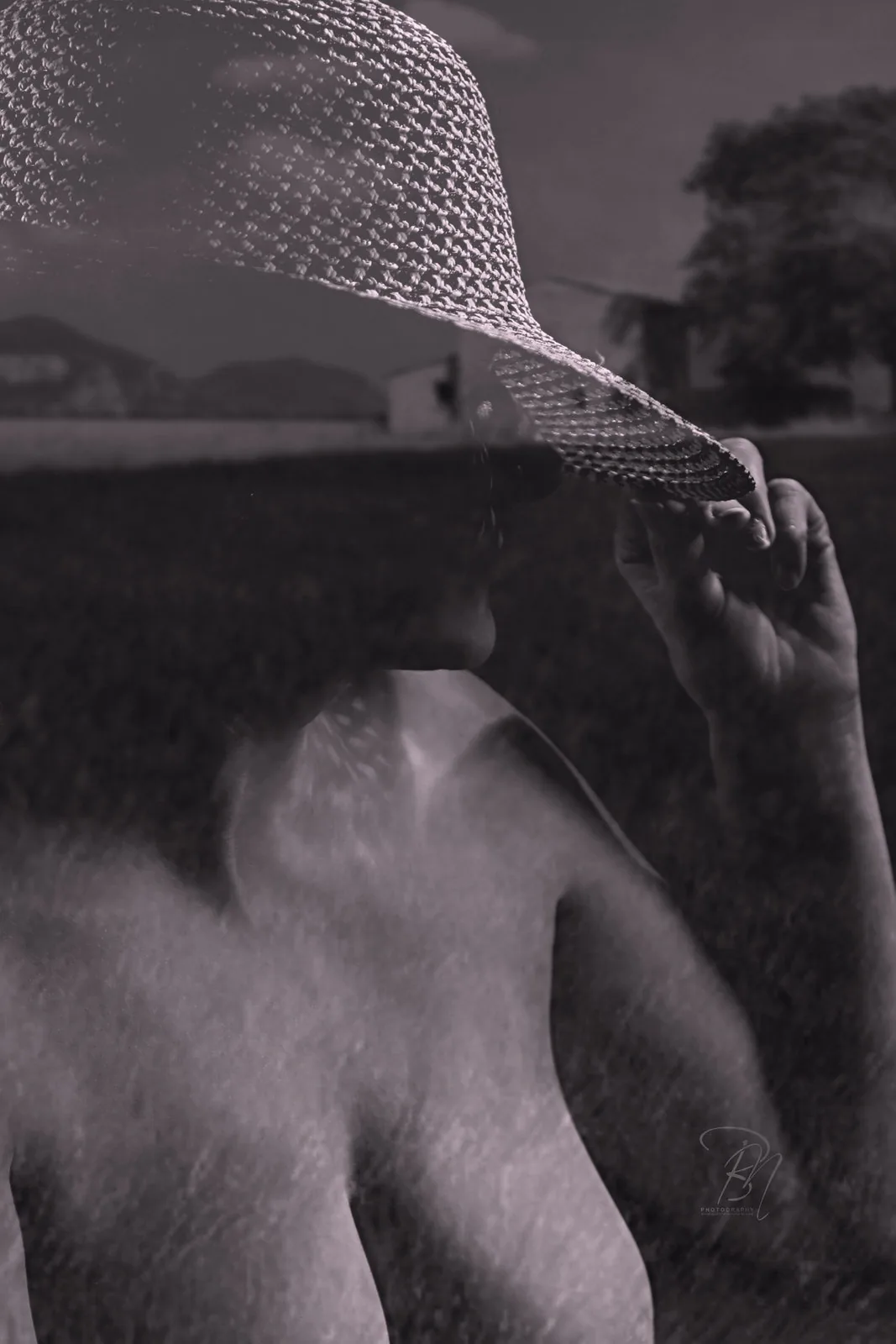 Veil in the field — Photo: Norbert Banhalmi A veiled face and a bare shoulder over an open field with a distant house.