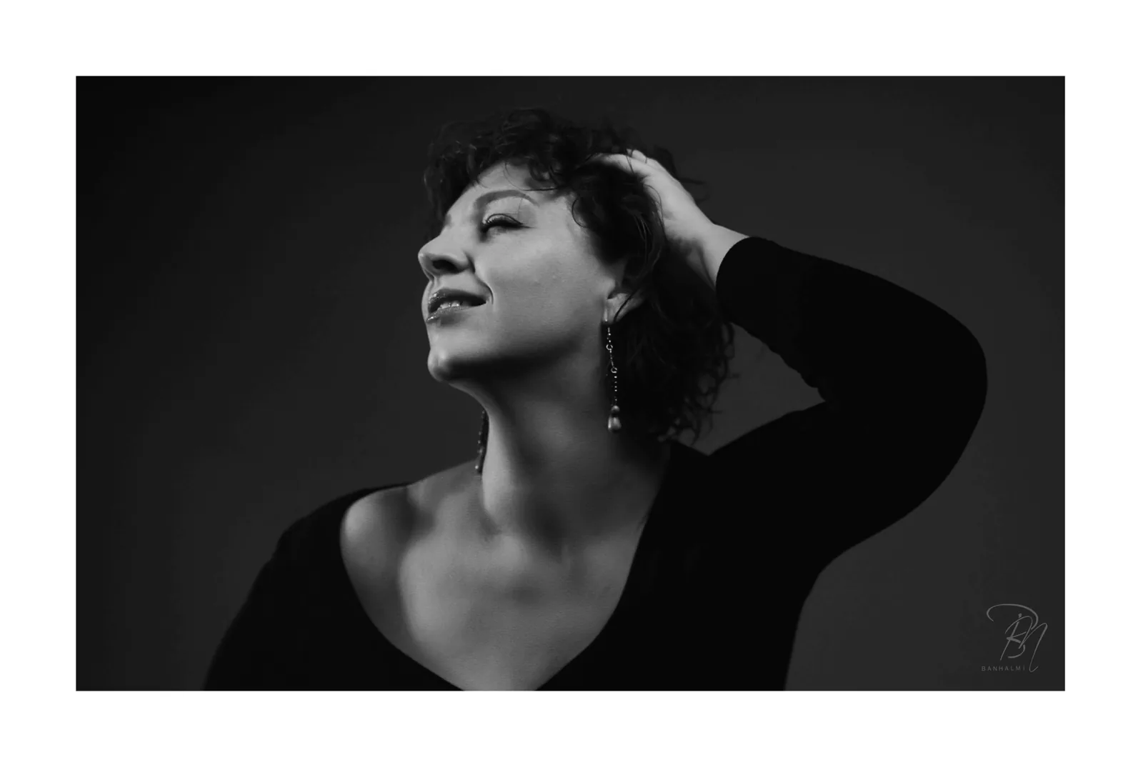 Hand in the hair — Photo: Norbert Banhalmi A woman turns her head to the light, one hand in her short hair.