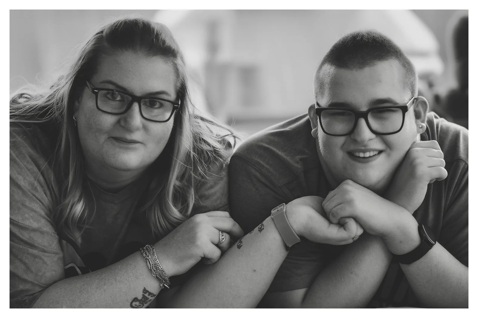 Two pairs of glasses — Photo: Norbert Banhalmi A woman and a boy, both in glasses, lean their heads together, arms folded in front of them.
