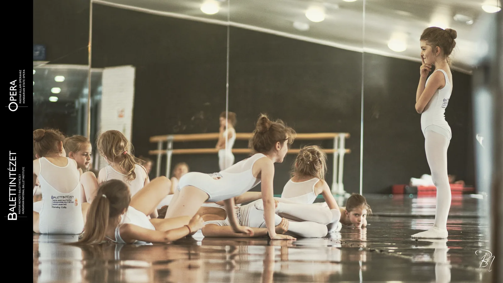 Rest in the studio — Photo: Norbert Banhalmi Students rest on the studio floor while one stands watching by the mirror.