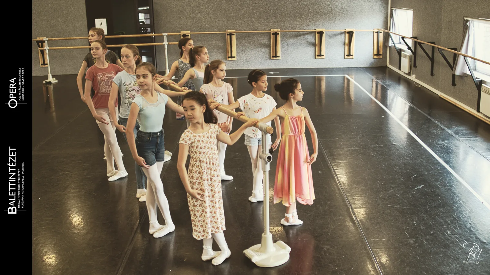 Circle — Photo: Norbert Banhalmi Children stand in a loose circle in a rehearsal room, holding hands.