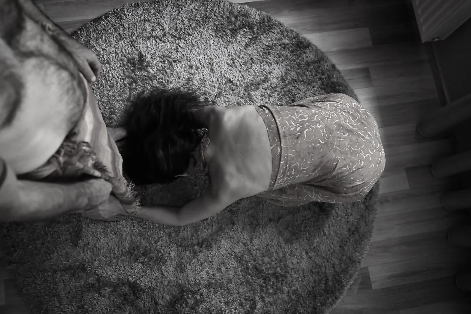 Seen from above — Photo: Norbert Banhalmi Overhead view of a person lying face down on a round rug while another leans over them.